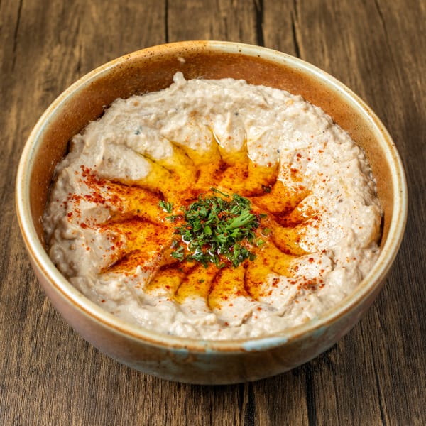 A bowl of Mediterranean baba ghanoush, garnished with olive oil, paprika, and fresh parsley.